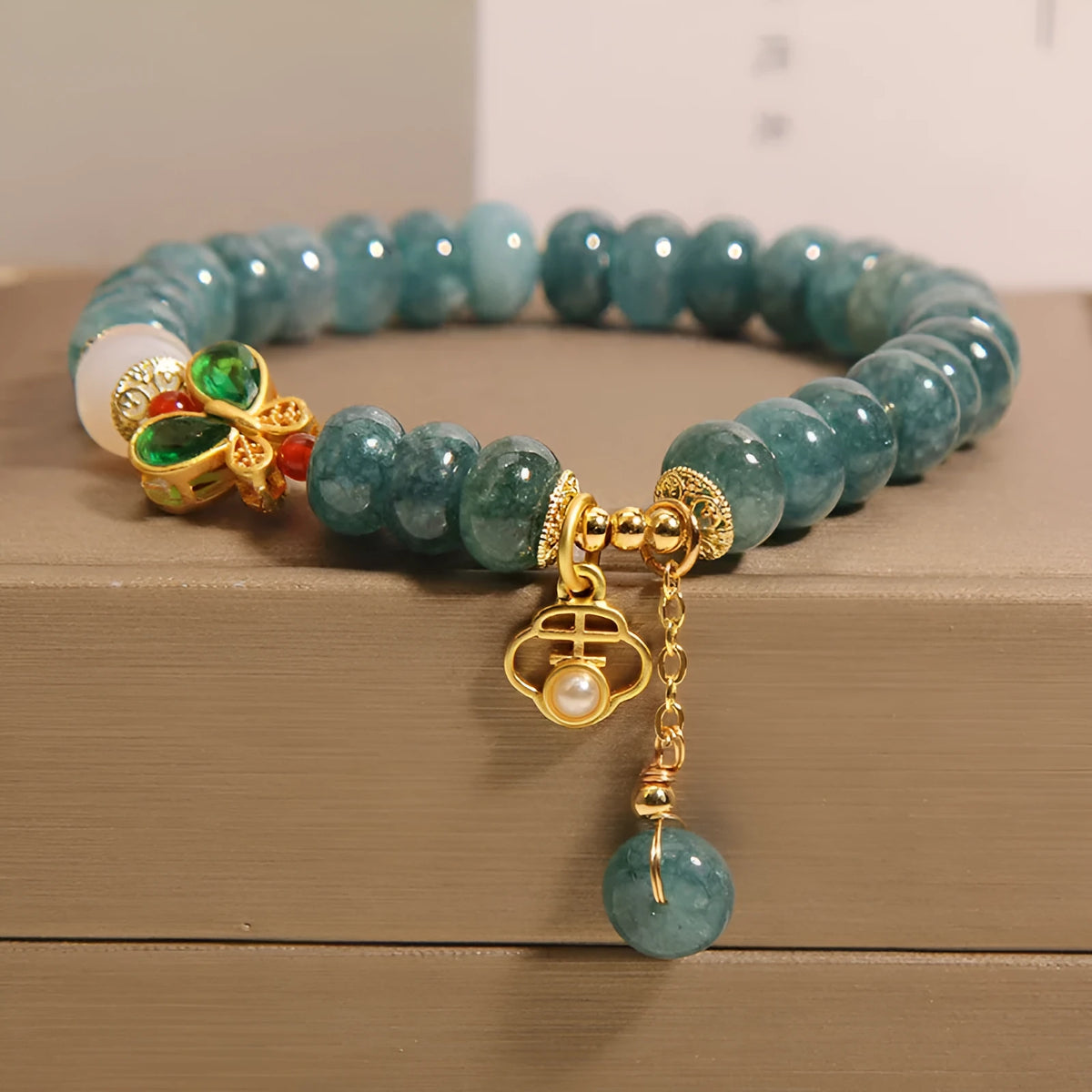 Women's blue water jade abacus bead bracelet with alloy charms, white agate, and rhinestone details
