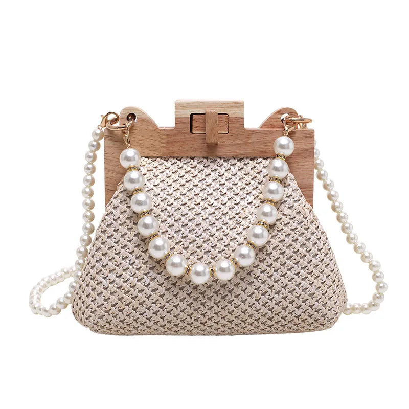 Women's horizontal square straw shoulder bag with pearl chain strap, shown in beige colour with visible sewing line detail.