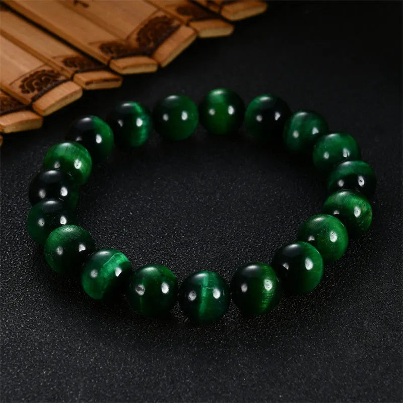 A green tiger eye stone beaded bracelet with geometric polished beads on an adjustable cord.
