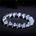Women's white crystal bracelet with ghost pyramid beads and a ruyi charm, shown on a wrist.
