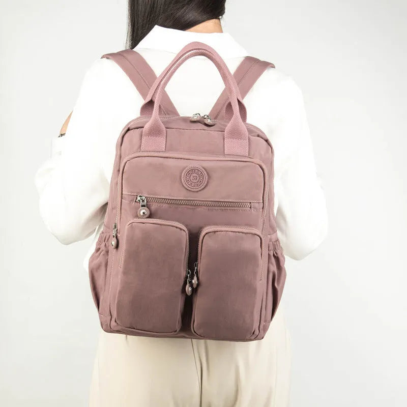 Large soft nylon waterproof backpack in grey, open to show internal laptop, camera, and phone compartments.