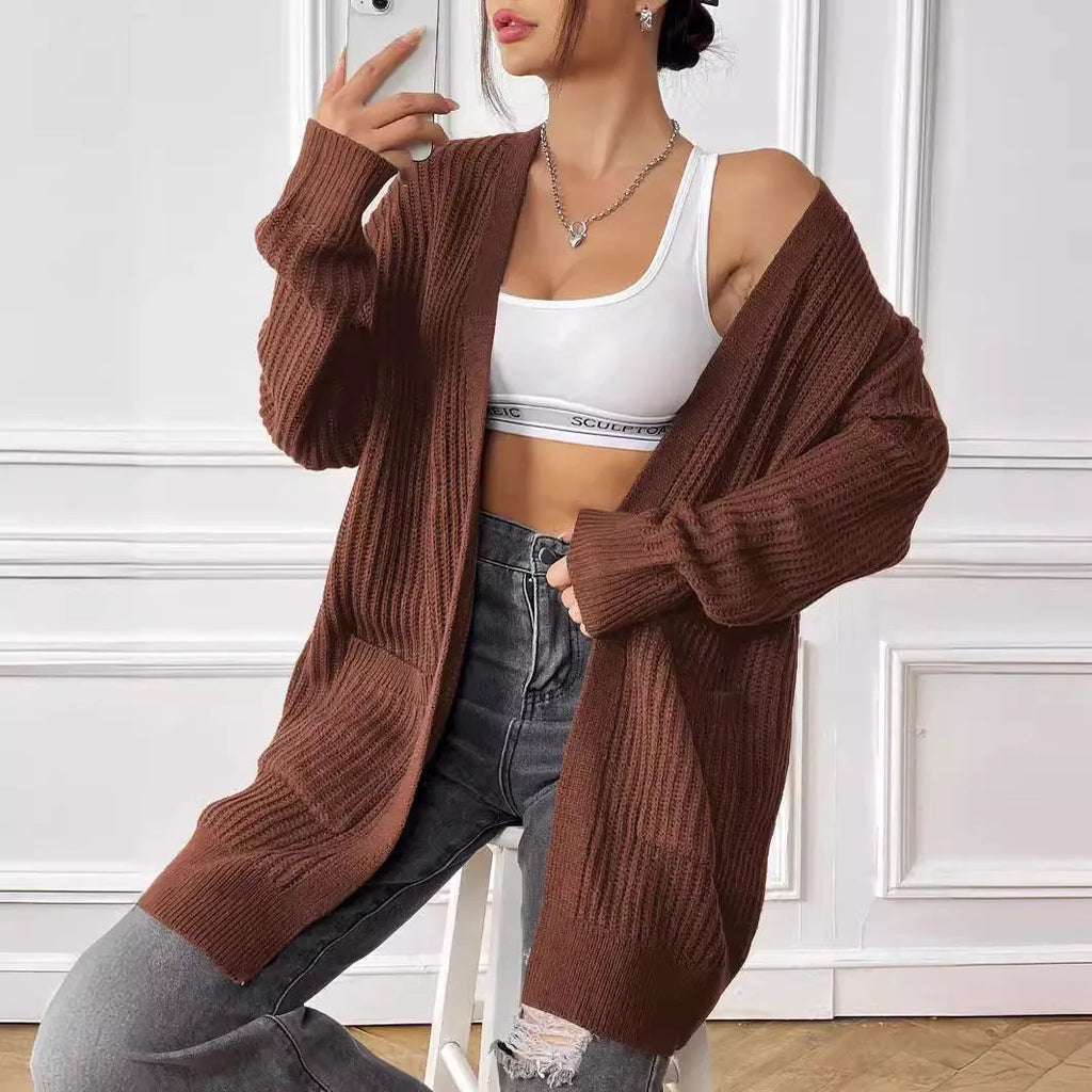 A loose-fitting, mid-length acrylic cardigan sweater in a solid colour, shown in a street hipster style.
