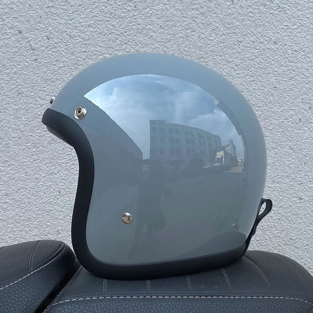Retro style fibreglass half motorcycle helmet shown in a choice of colours like cement grey and matte black.