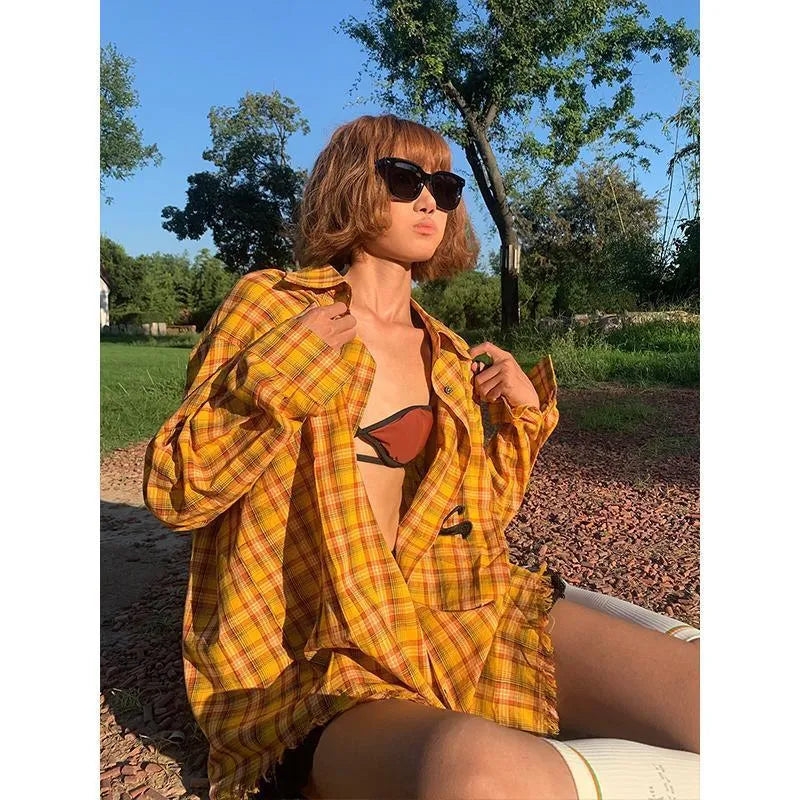A man or woman wearing a loose-fitting yellow plaid cardigan-style shirt.
