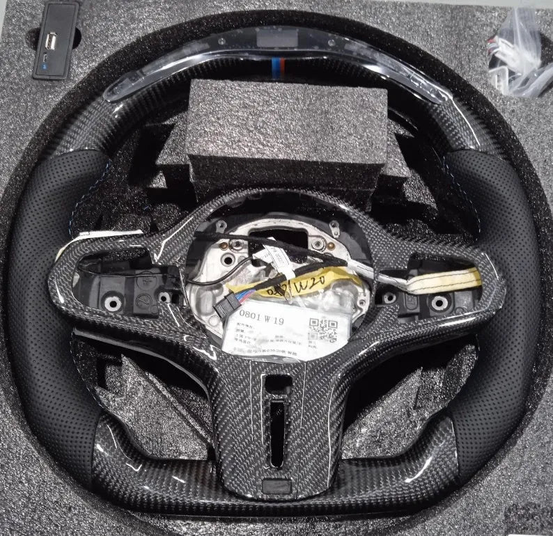 Black carbon fibre BMW sports steering wheel with LED display and multifunctional buttons.