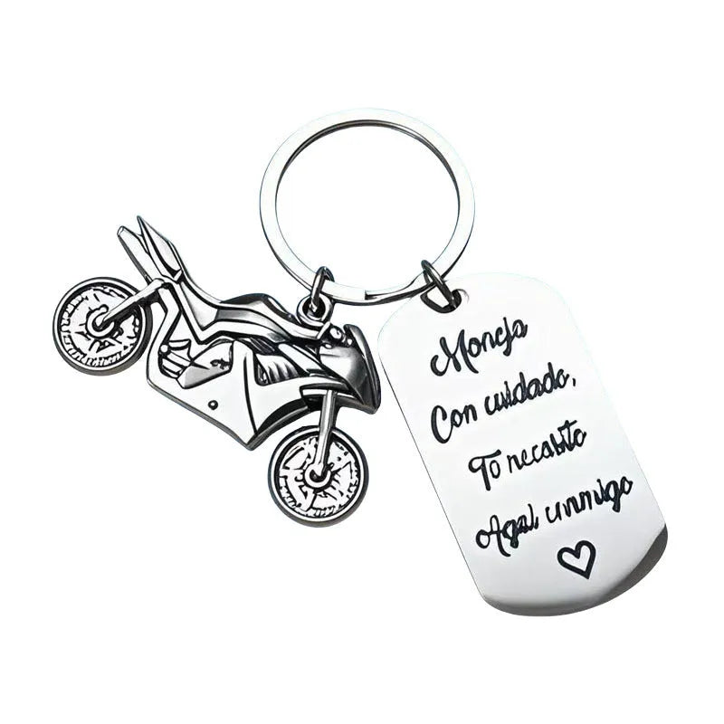 Stainless steel motorcycle key ring with velvet storage bag on a plain background.