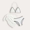 Solid white three-piece girls swimsuit set with top, pants, and skirt on a beach setting.