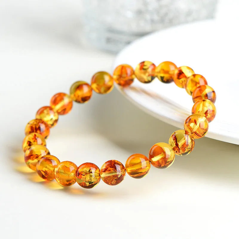 Natural yellow piebald amber bracelet with geometric beads on wrist.