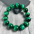 A green tiger eye stone beaded bracelet with geometric polished beads on an adjustable cord.