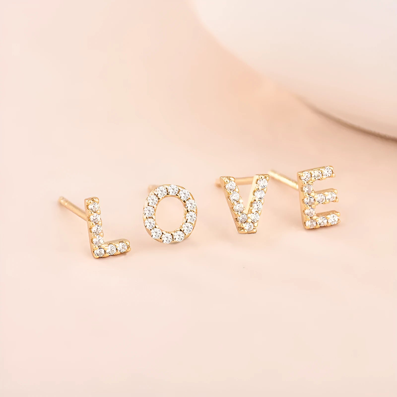 Gold plated brass alphabet letter earrings on a white background, showing zircon detail.