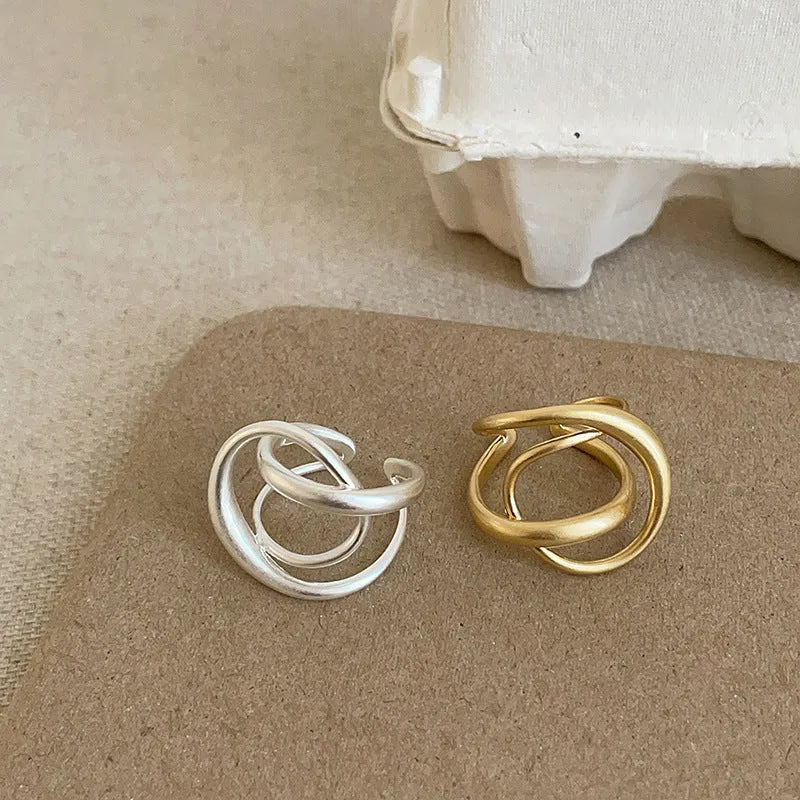 Geometric open ring for women with 3D interlaced matte metal design in gold and silver colour options.