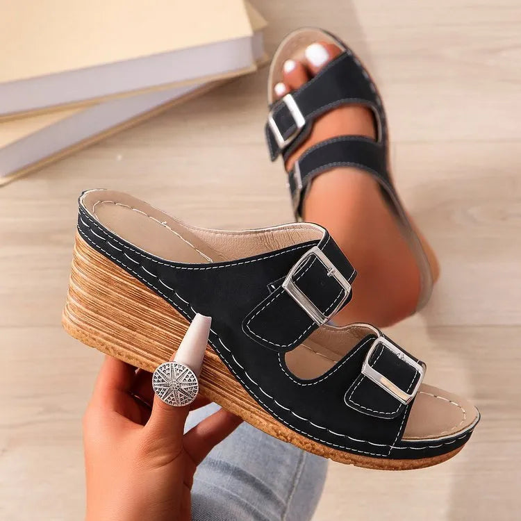 Women's creamy-white beach slippers with a black outer wedge belt buckle closure on a rubber sole.