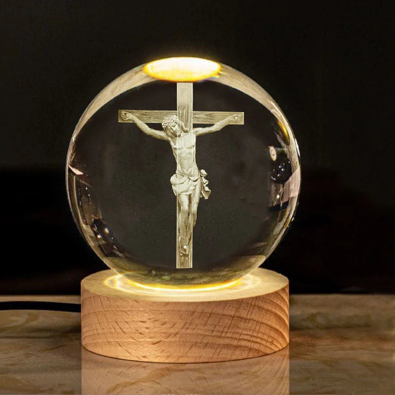 White crystal ball ornament on wooden base with religious symbols and warm light illumination