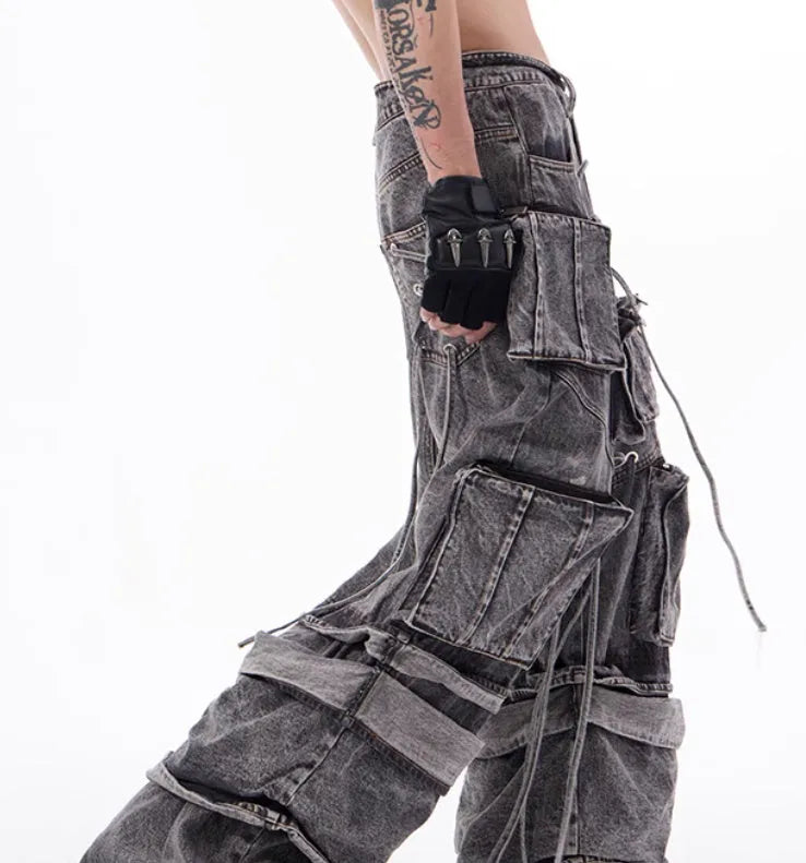 A pair of grey distressed denim overalls with rope stitching, shown on a model.