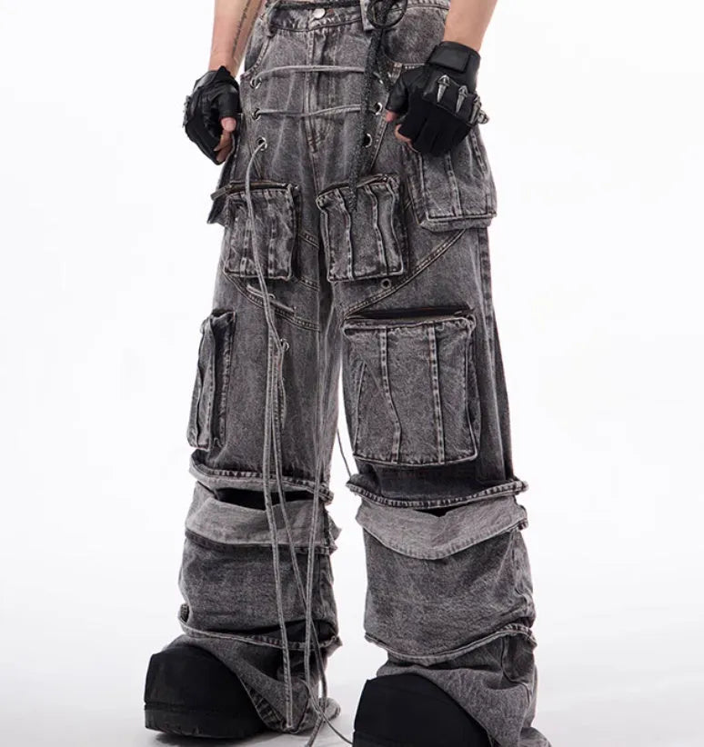 A pair of grey distressed denim overalls with rope stitching, shown on a model.