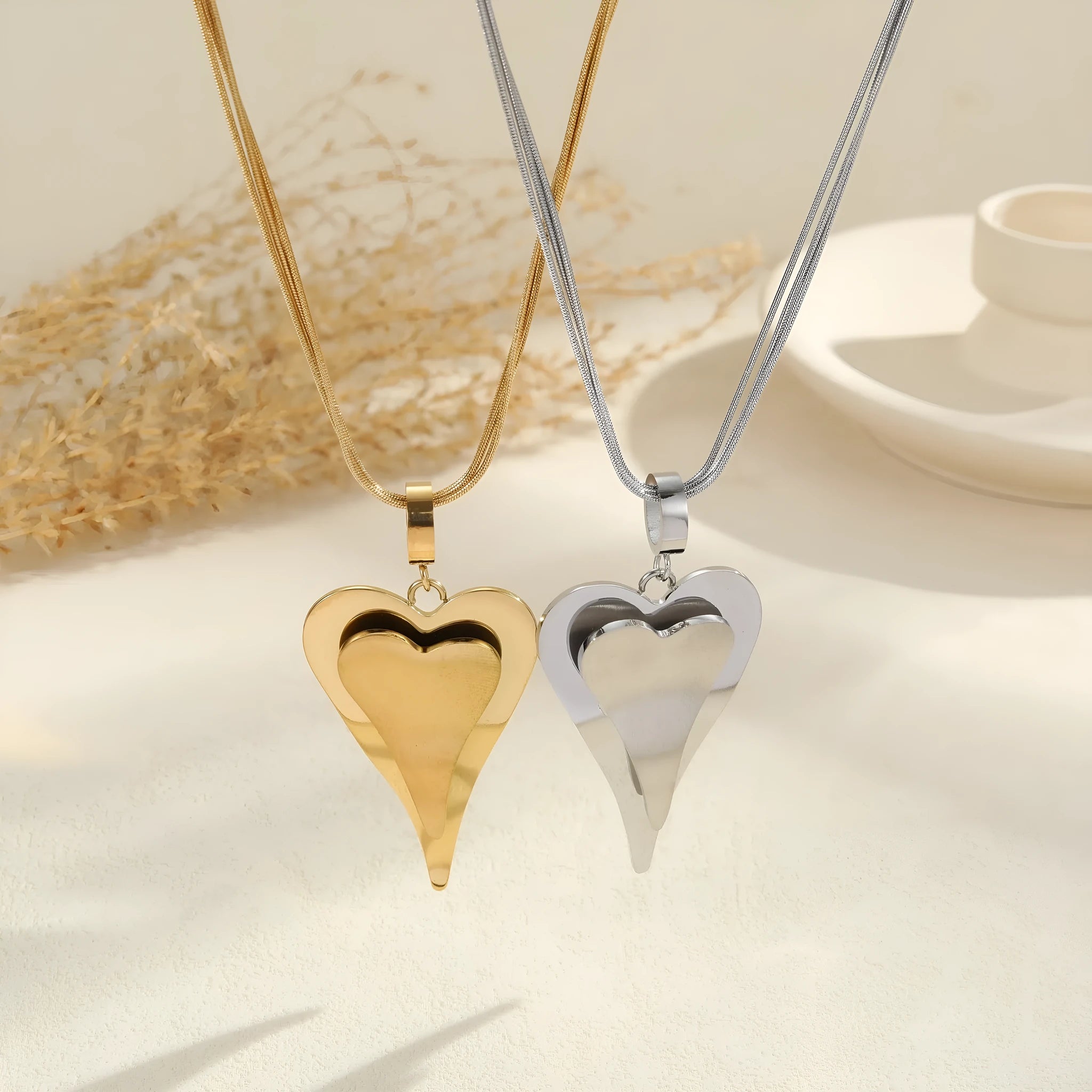 Stainless steel women's necklace with double heart geometric pendant on a snake bones chain.