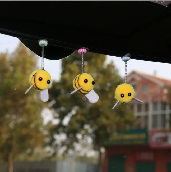 Small, soft, cartoon bee car decoration made from yellow and black fur ball material.