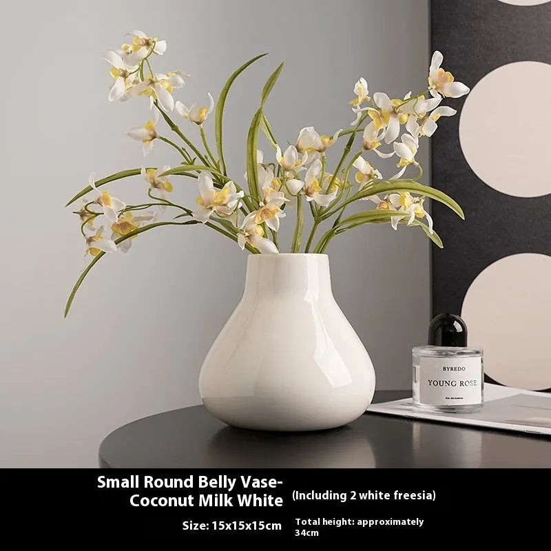 Black ceramic vase with round belly shape and two white flower ornaments arranged decoratively