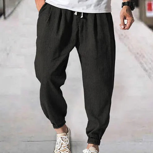 Man wearing light-coloured cotton banded ankle pants with a loose, casual fit.