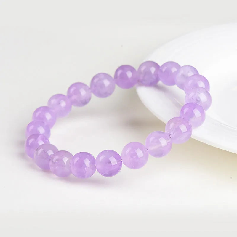 Lavender round amethyst bead bracelet with geometric water ripple design on a wrist.