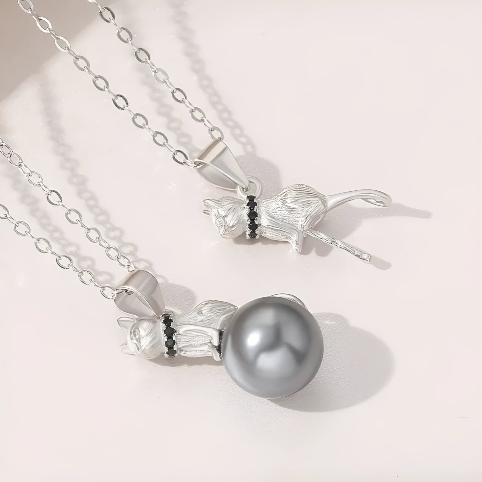 Close-up of a sterling silver cat pendant necklace on a chain with an electroplated finish.
