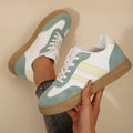 Green women's retro sports pumps with cross straps, flat rubber sole, and round toe on a white background.