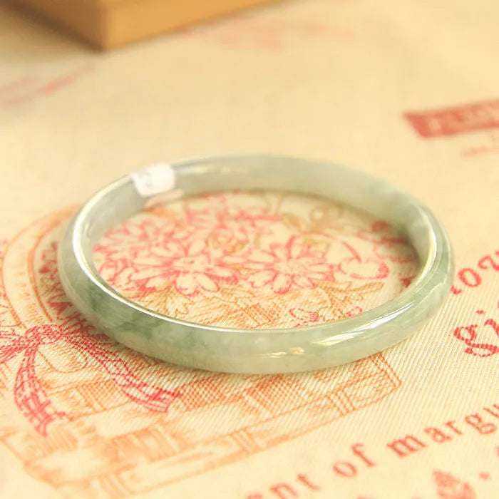 Green jade waxy stone geometric bracelet with Chinese style design on a wrist.