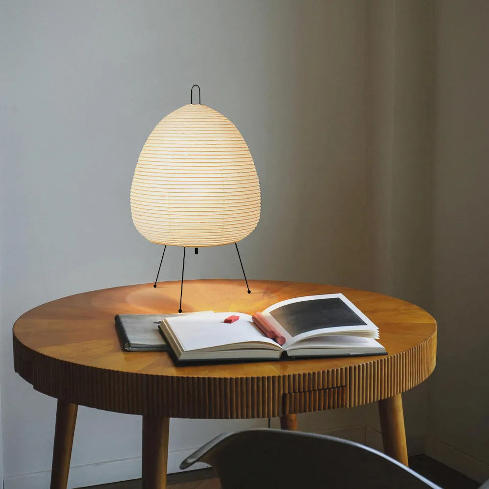 Nordic style table lamp with a handmade Japanese rice paper shade and aluminium base on a wooden table.