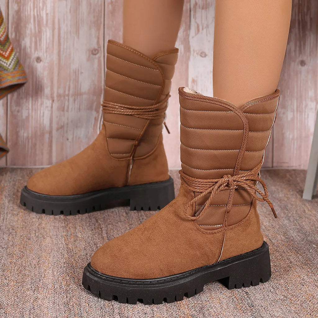 Women's black chunky heel snow boots with suede upper and lace-up design on a white background.