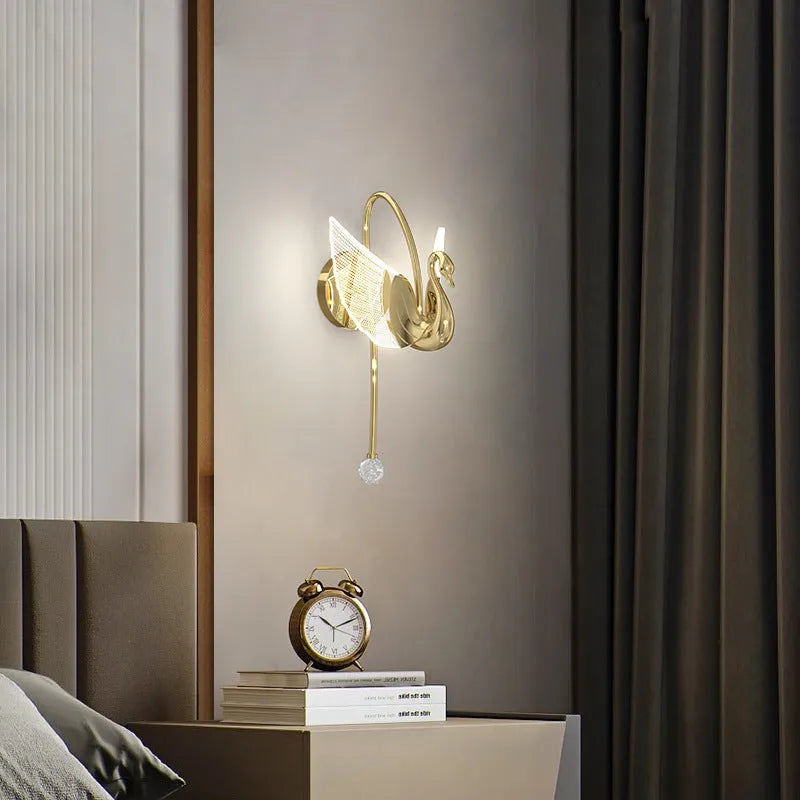 Gold swan-shaped modern minimalist wall lamp with acrylic shade on a wall.