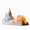 Mountain-shaped night light with LED touch control, essential oil bottle, and gift card on a wooden desk