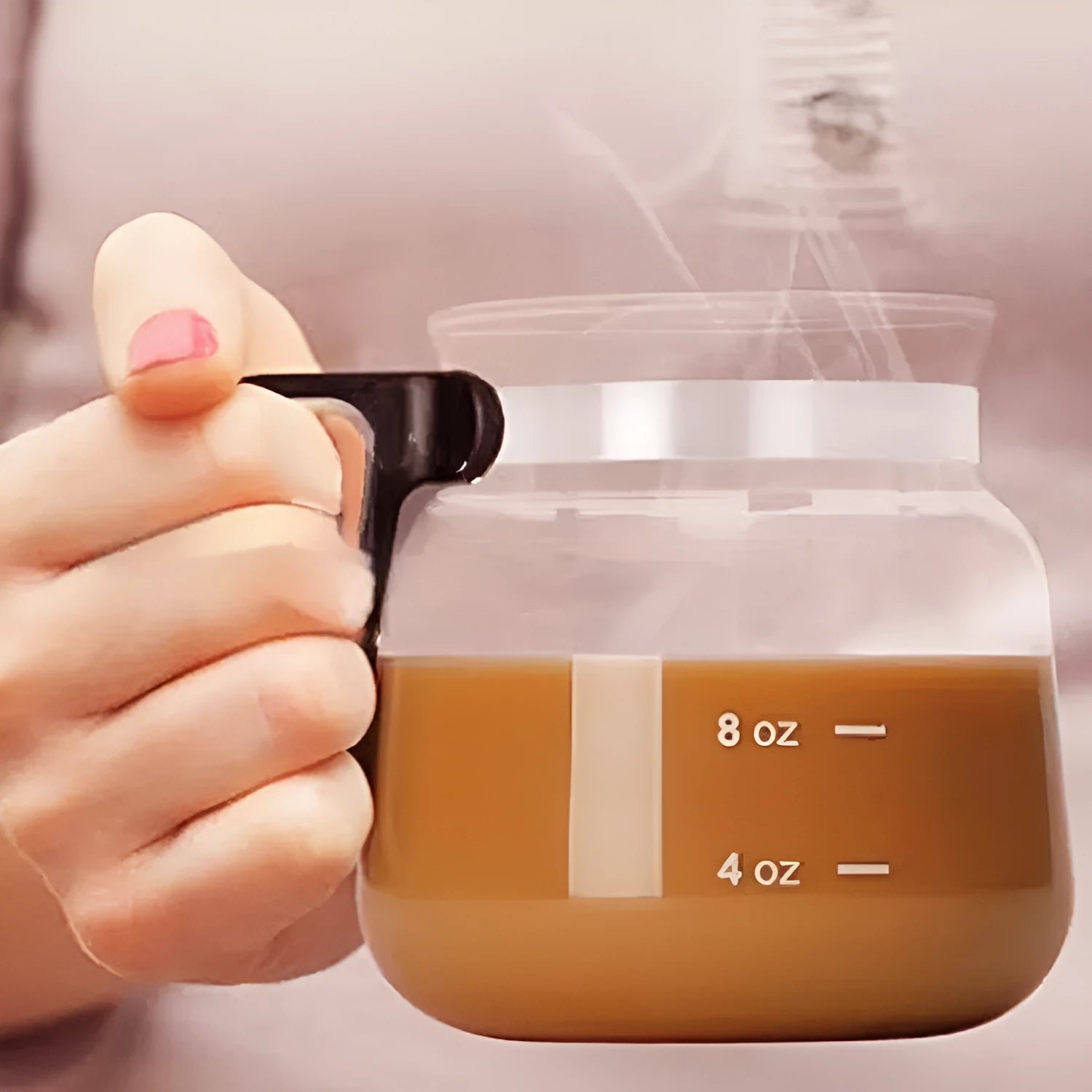 Transparent borosilicate glass coffee maker with black silicone cover and handle on a stovetop.