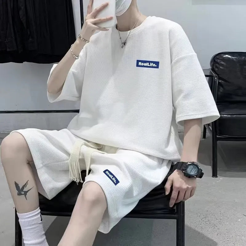 Man wearing a grey waffle-textured short sleeve leisure top and matching shorts.