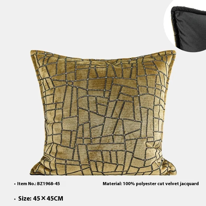 Gold geometric abstract patterned square cushion on a grey sofa.
