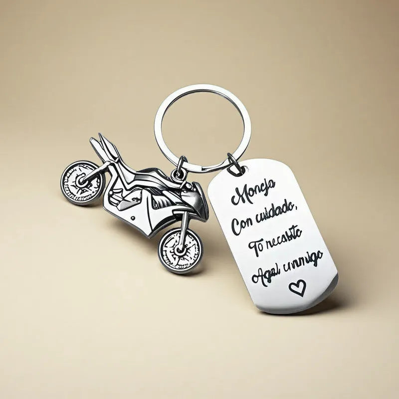 Stainless steel motorcycle key ring with velvet storage bag on a plain background.