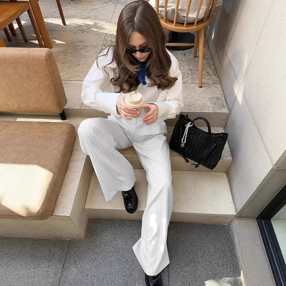 White striped wide-leg women's trousers with a loose fit and zipper fastening on a hanger.