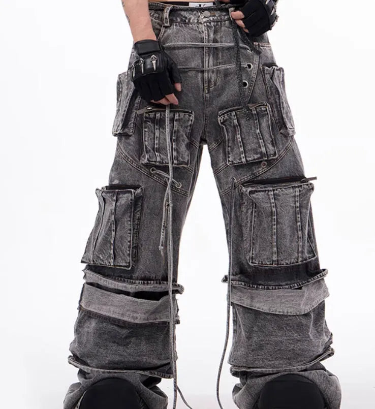A pair of grey distressed denim overalls with rope stitching, shown on a model.