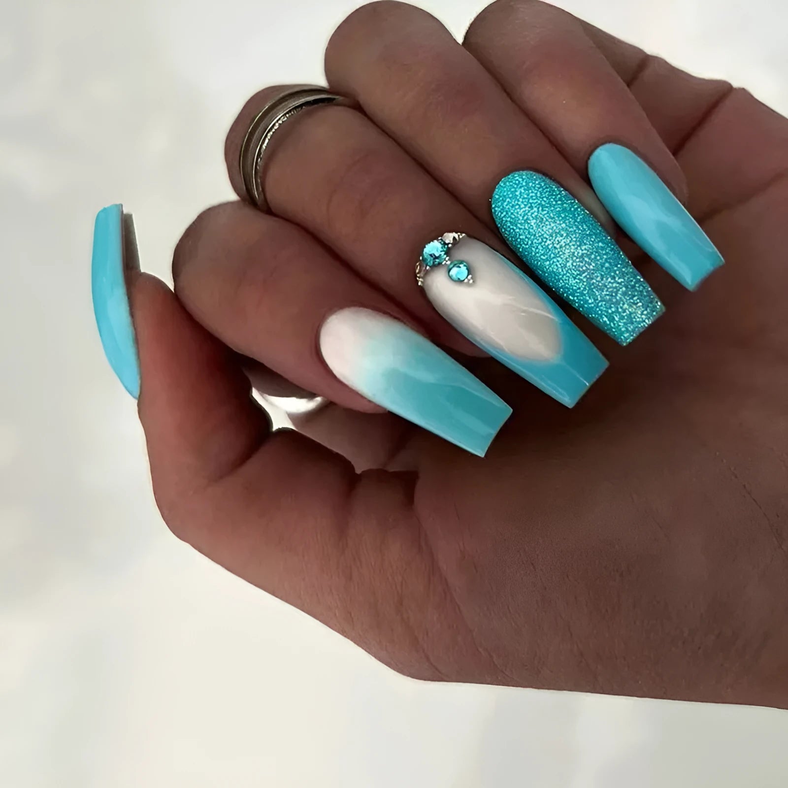 Long smart blue diamond false ballet nails with glitter particles and glue tube.