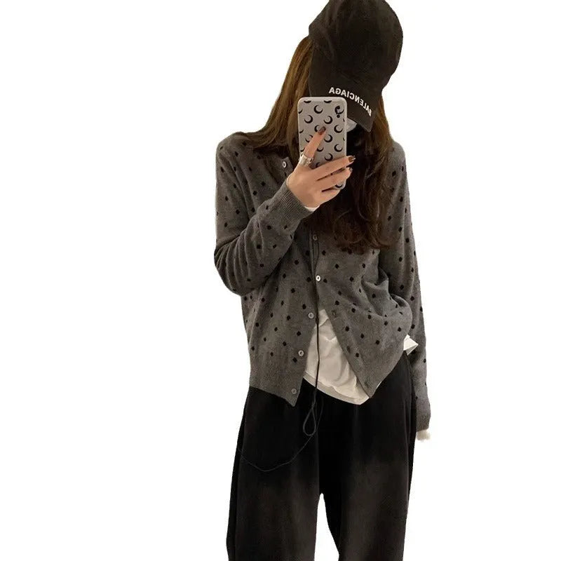 Women's grey dot pattern knitted cardigan with crocheted flower detail on a mannequin.
