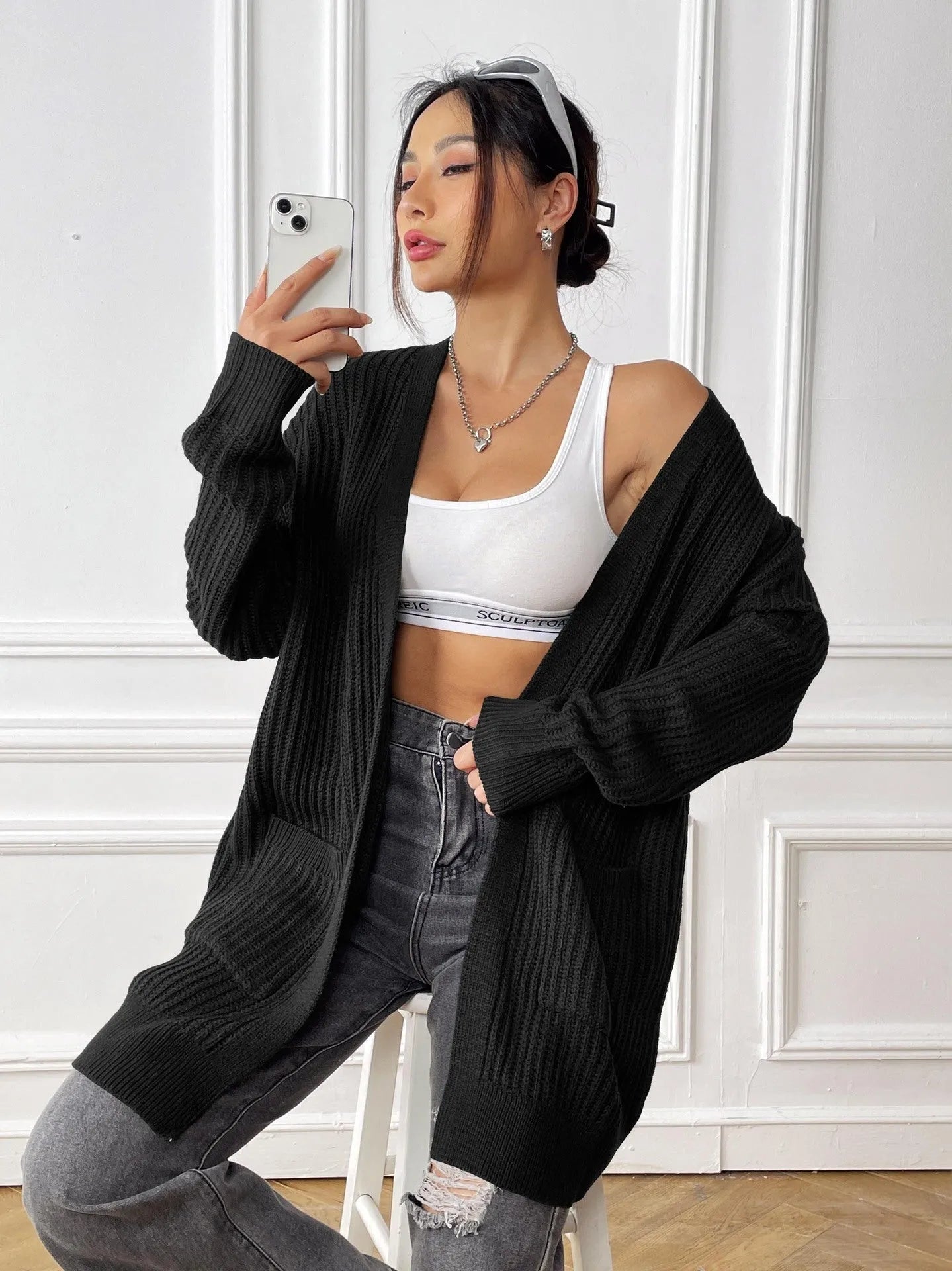 A loose-fitting, mid-length acrylic cardigan sweater in a solid colour, shown in a street hipster style.