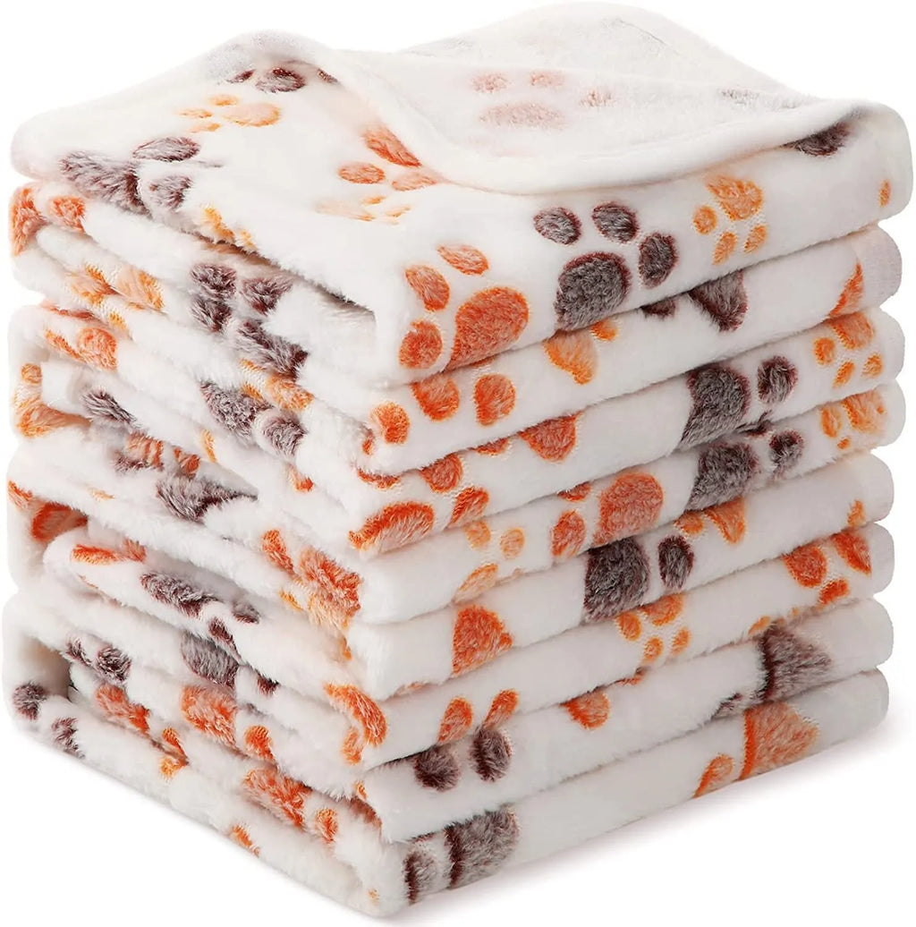 Coral fleece pet blanket with dog paw print pattern in beige, shown alongside size options from small to extra large.