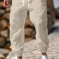 Men's straight-leg linen trousers with elasticated waistband in apricot colour on a hanger.