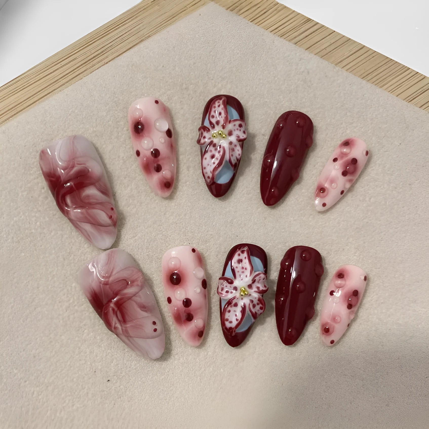 Hand-painted three-dimensional carved almond artificial nail extensions showing rose and tulip patterns