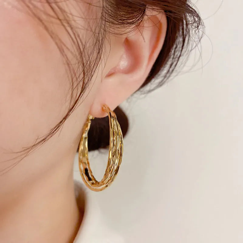 Gold metal twisted earrings with round geometric shape on copper base