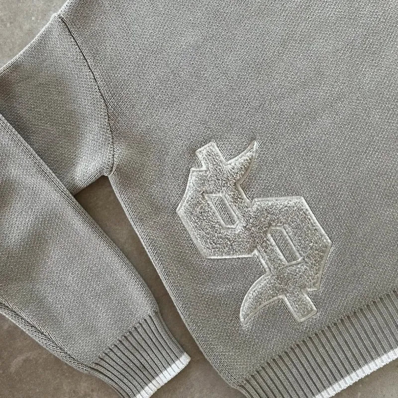 Grey loose-fitting jacquard knitwear coat with long sleeves on a hanger.