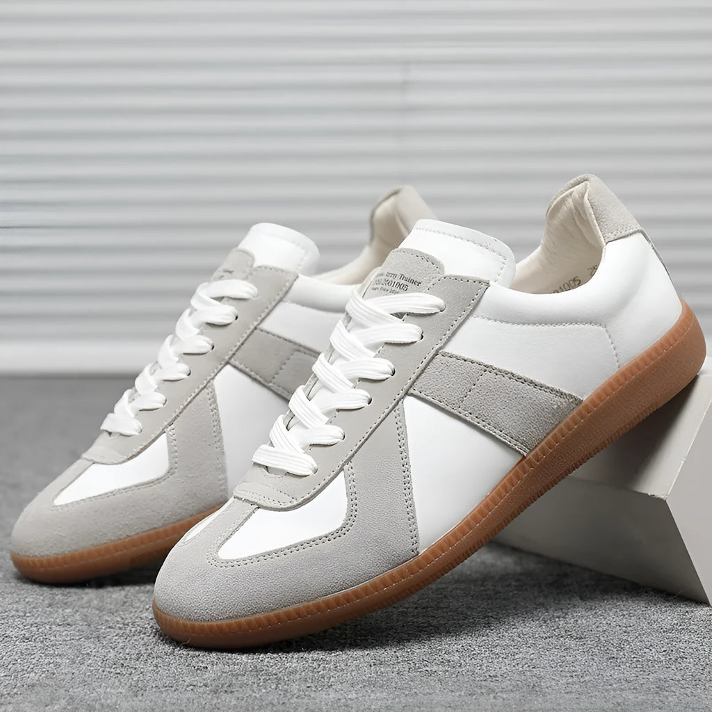 White low-top retro sneakers with mesh lining and rubber soles on a solid background