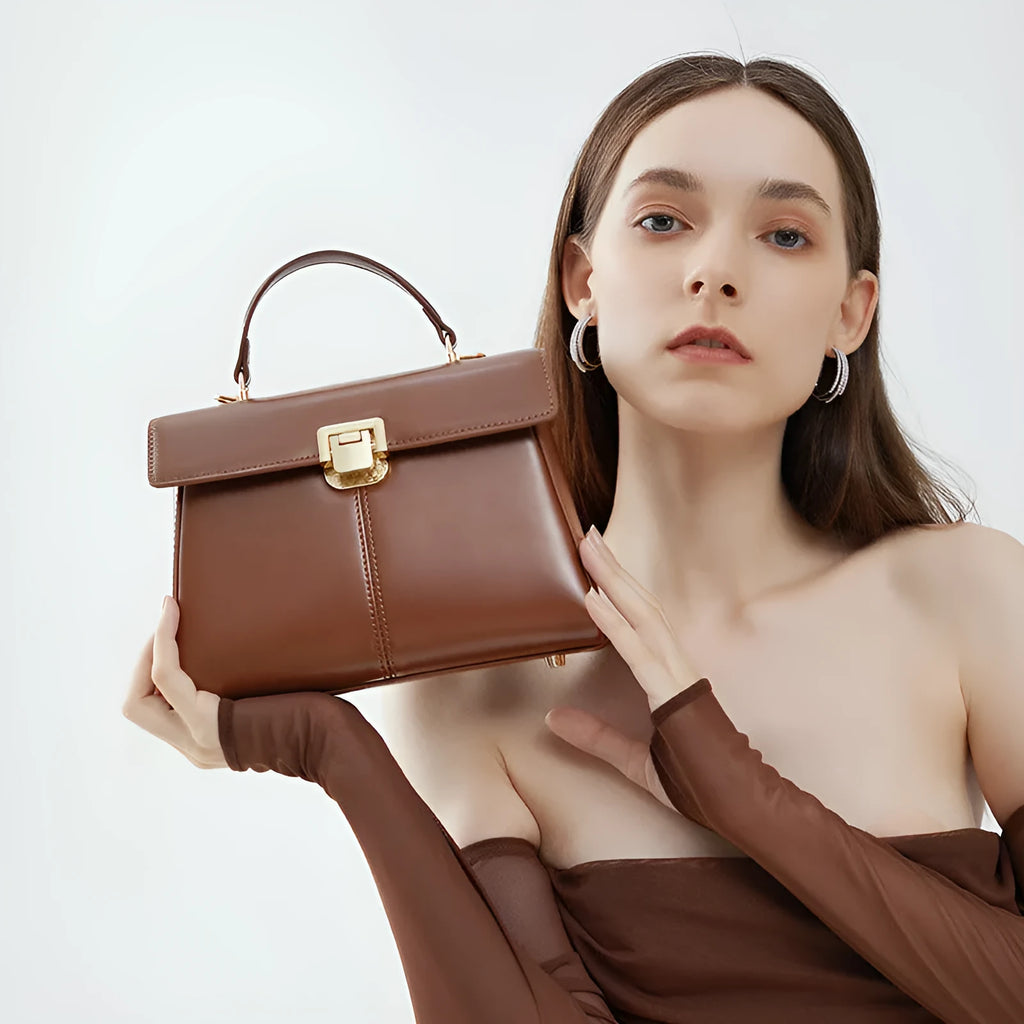 Women's black leather shoulder bag with vachette clasp showing horizontal square shape and adjustable strap