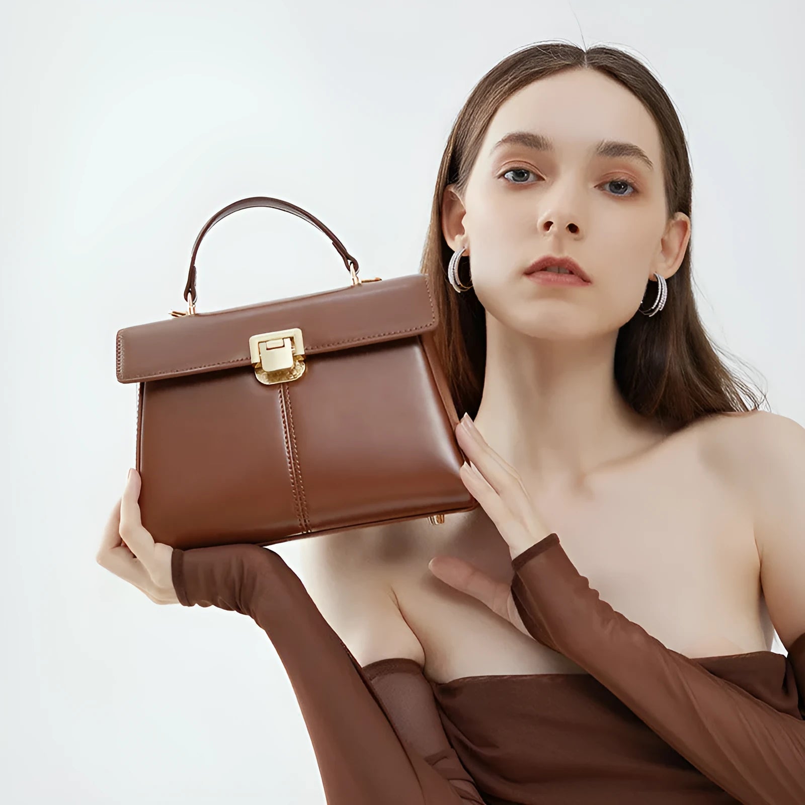 Women's black leather shoulder bag with vachette clasp showing horizontal square shape and adjustable strap
