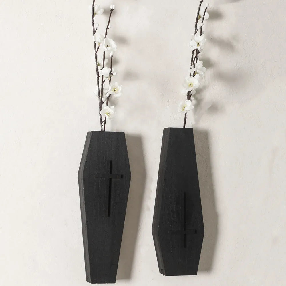 Black wooden cross-shaped wall shelf with space for holding small plants or decorative items.
