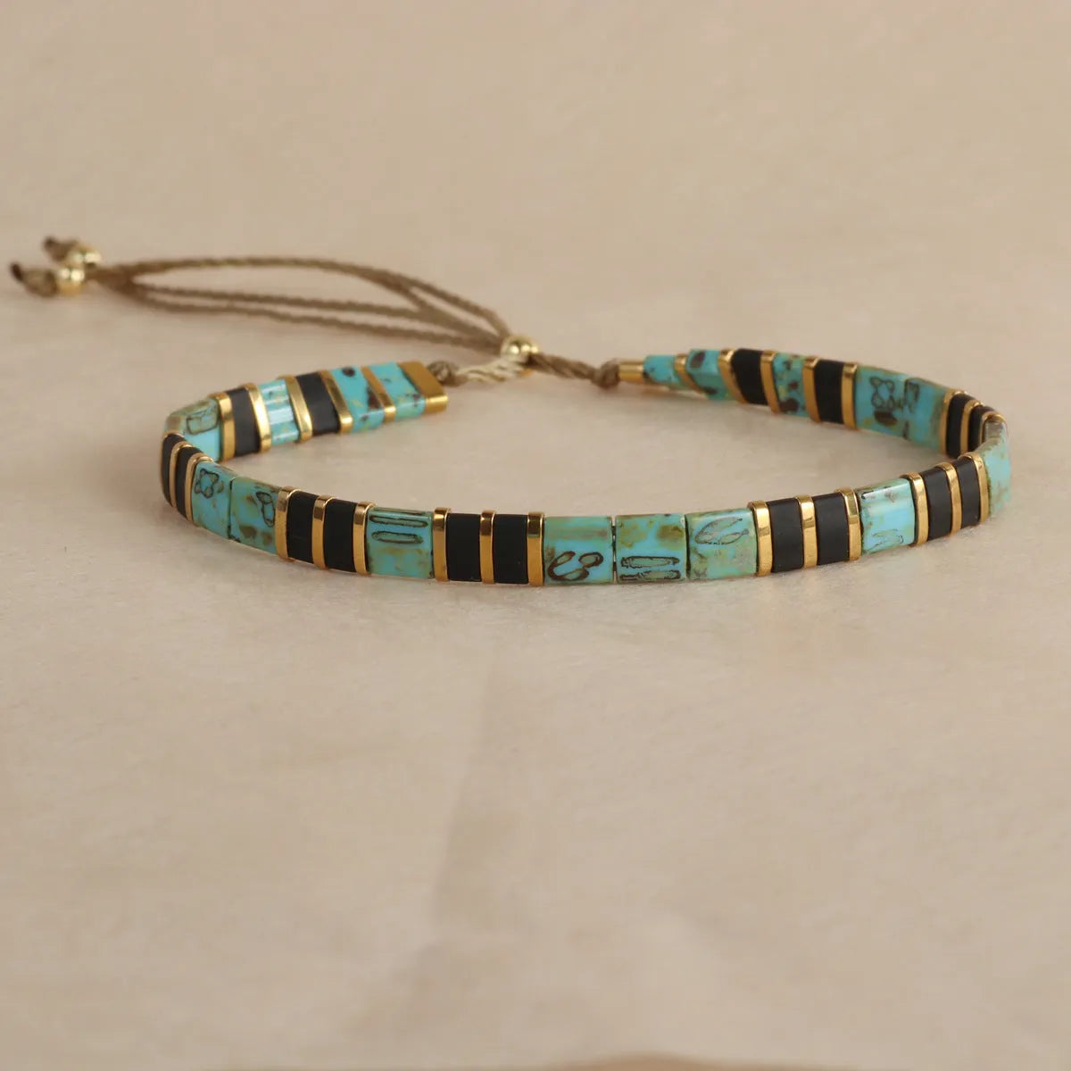 Geometric glass and coloured glaze beaded bracelet with a pull clasp in milky white colour.